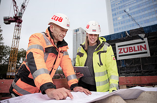 Foto av ZÜBLIN-kollegor som diskuterar något utifrån en konstruktionsplan