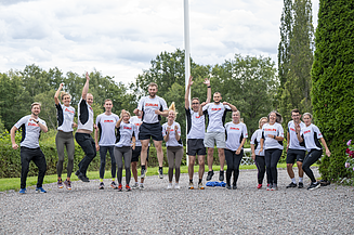 Tre kvinnor ler mot kameran och håller upp STRABAG-vattenflaskor mot linsen.