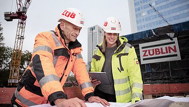 Foto av ZÜBLIN-kollegor som diskuterar något utifrån en konstruktionsplan